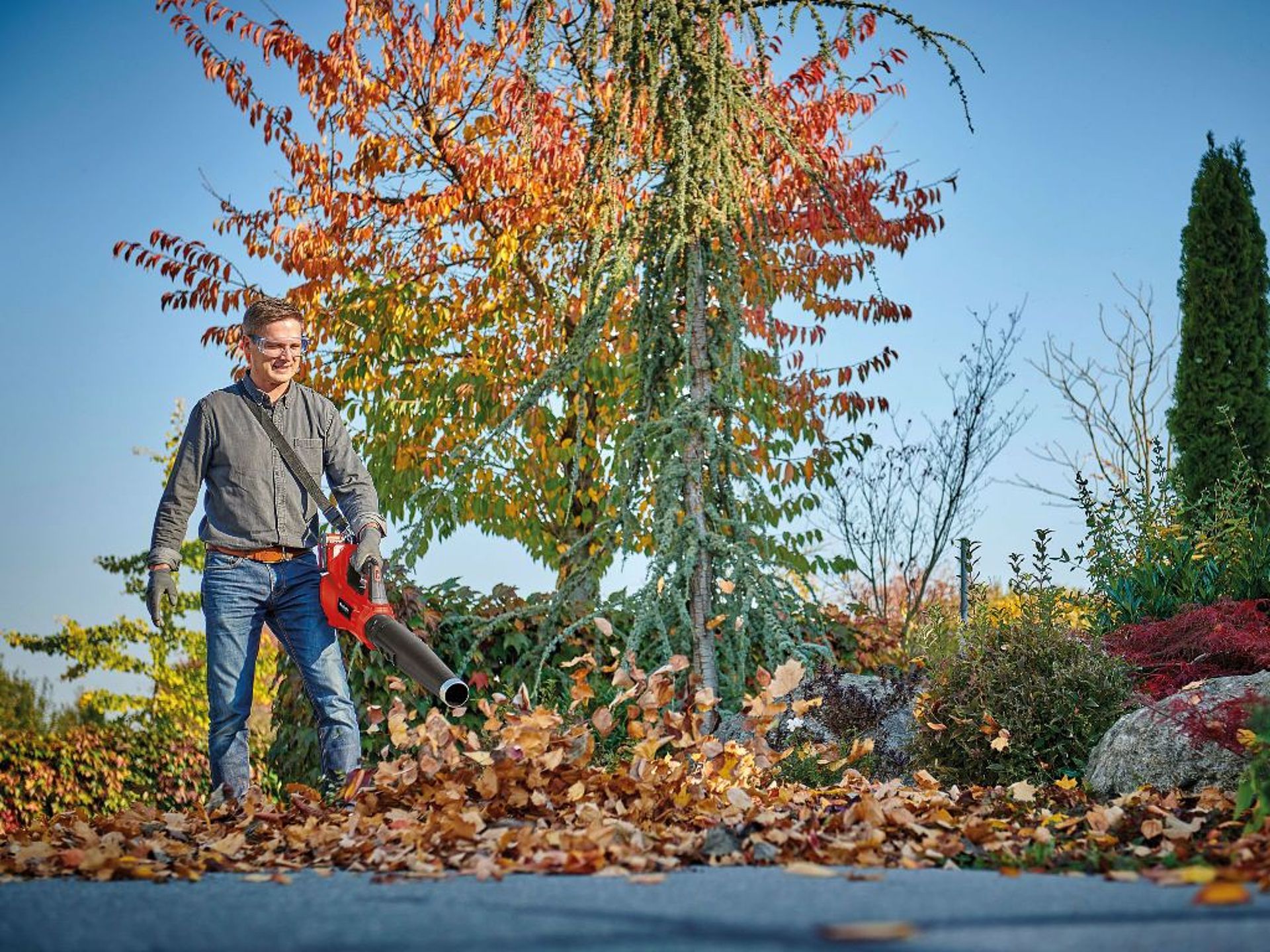 A man is wearing protective gear while using a leaf blower